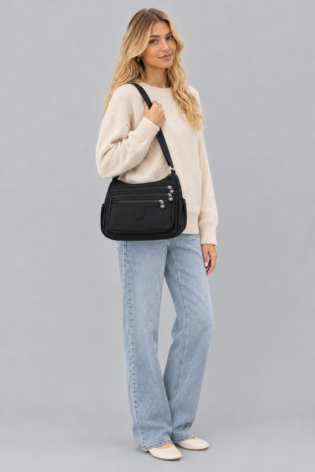 Femme en pied, nouvelle pose, sac Lara noir sur fond gris uniforme