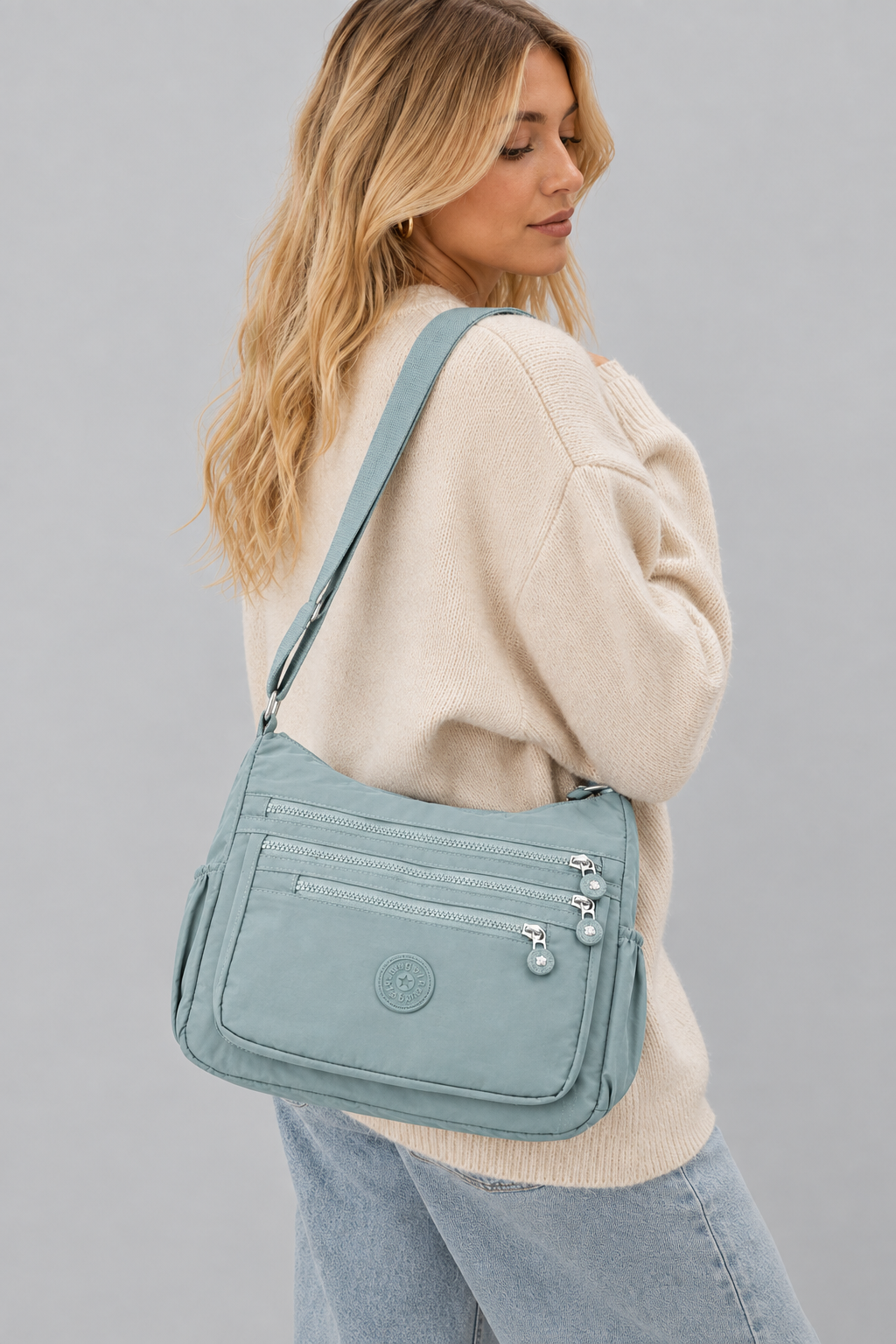 Femme portant le sac Lara bleu sur fond gris uniforme