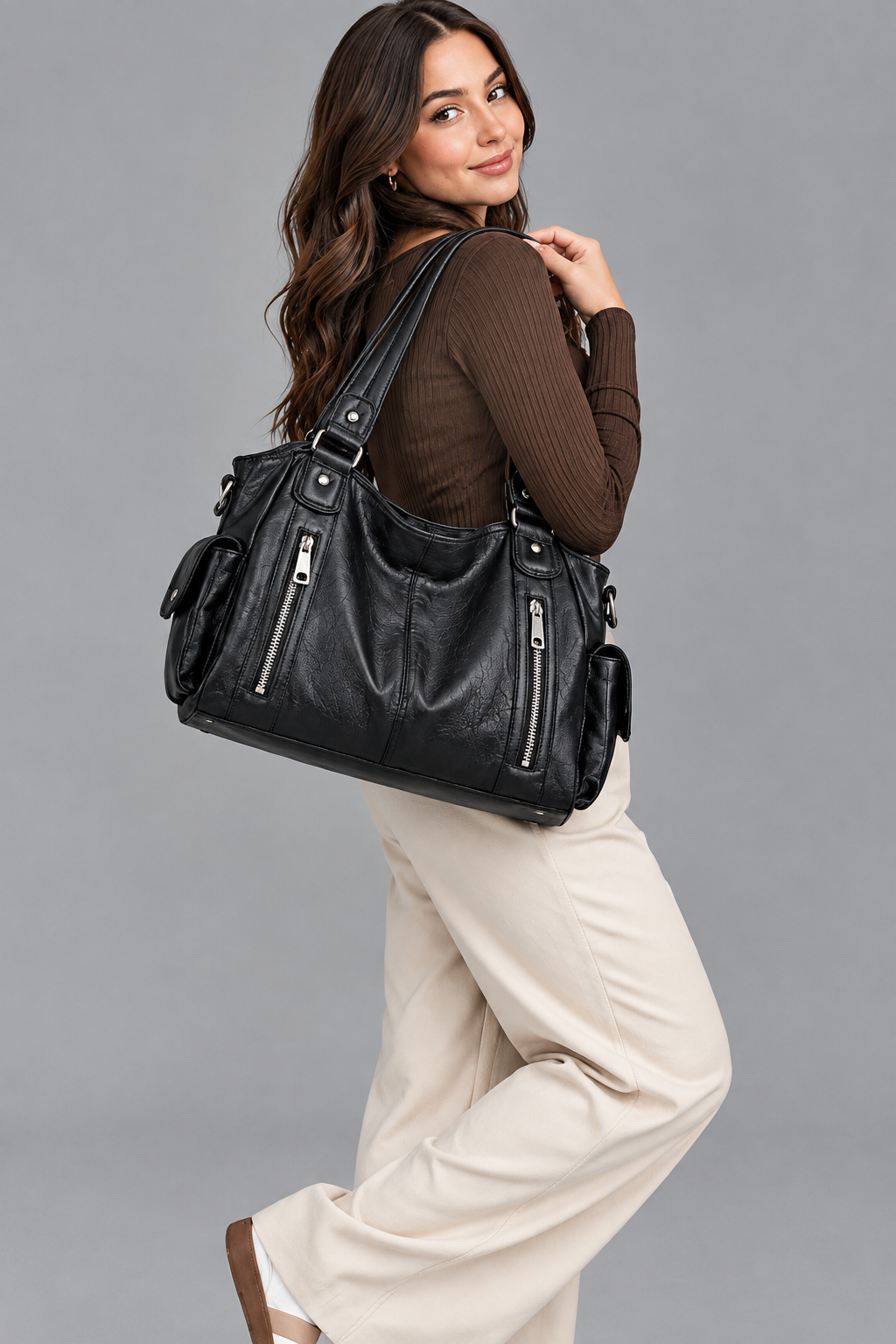 Femme portant le sac noir à l'épaule, photo nette sur fond gris
