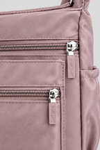 Zoom sur la matière nylon mauve du sac Rosa et son zip argenté, fond gris uniforme