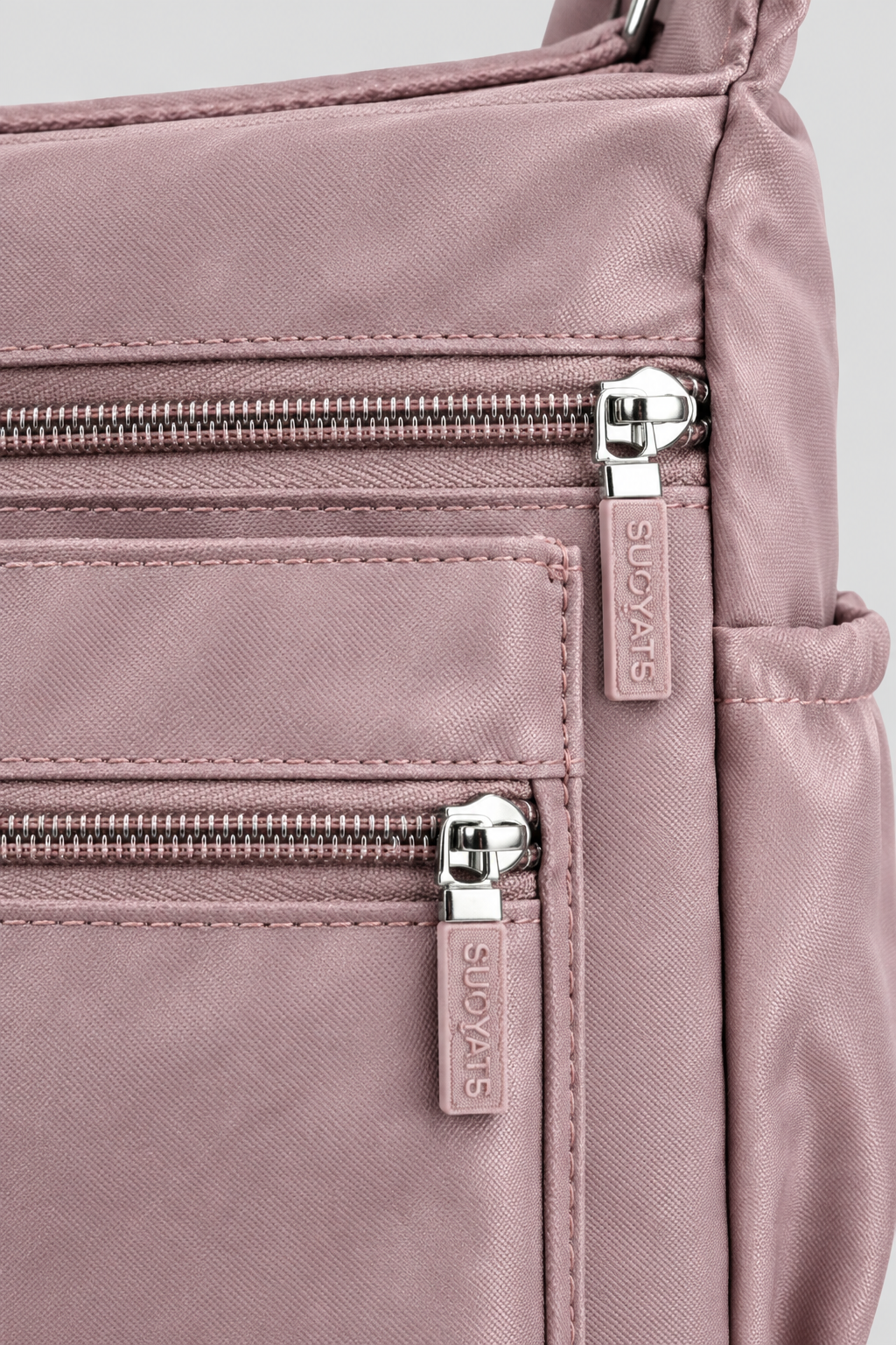 Zoom sur la matière nylon mauve du sac Rosa et son zip argenté, fond gris uniforme